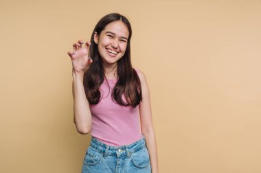 Pembe bluzlu ve kot pantolonlu gülümseyen kadın neşeli bir jest yapıyor..