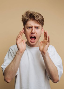 Gündelik giyinmiş genç bir adam yoğun duygular gösterir, ellerini kaldırarak bağırır. İfadesi aciliyet ve tutku taşıyor. Dikkatleri sessiz bir ortamda onun duygularına çekiyor..