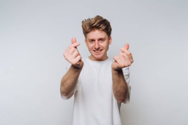 Genç bir adam elleriyle küçük kalp şekilleri yaparken gülümsüyor..