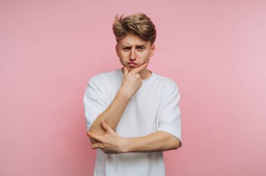 Kolları çapraz duran genç bir adam, bir eli çenesinde, derin düşüncelere dalmış. Parlak pembe bir arka planı olan kentsel bir çevrede modern ve canlı bir hava yaratıyor..