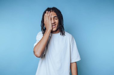 Rastalı genç adam gülüyor ve elleriyle yüzünü örtüyor..