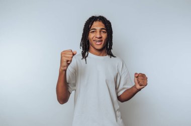 Örgülü saçlı genç adam yumruklarıyla kutlama yapıyor..