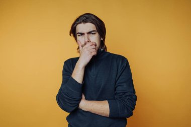 Turuncu arka planda düşünceli bir adam.