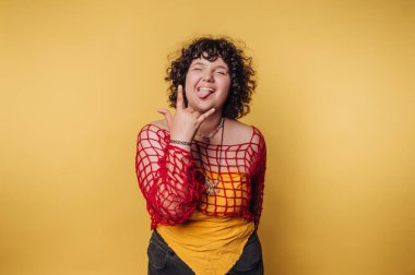 Kırmızı elbiseli kadın sarı arka planda neşeli bir jest yapıyor..