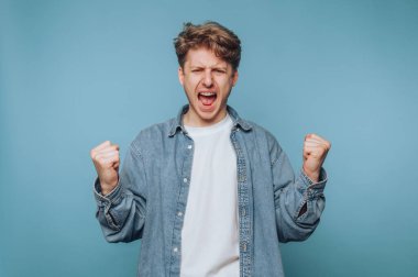 Kot gömlek giymiş, yumruklarıyla kutlama yapan genç bir adam..