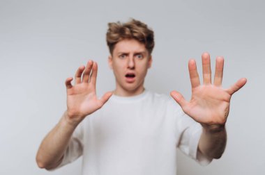 Beyaz tişörtlü, yüzünde bir ifade olan genç adam ellerini kaldırdı..