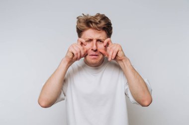 Beyaz tişörtlü bir adam ağlıyor gibi yapıyor..