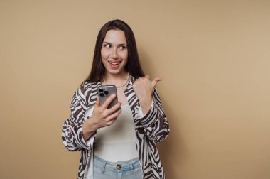 Akıllı telefon tutan kadın, işaret eden parmak, bej arka plan.