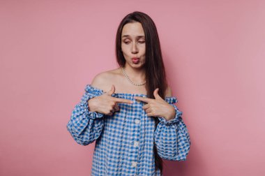 Mavi elbiseli kadın pembe arka planda poz veriyor.