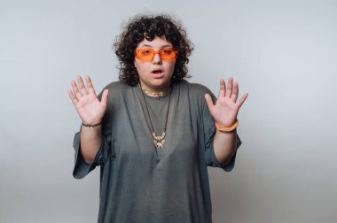 Kıvırcık saçlı ve turuncu gözlüklü biri şaşırmış görünüyor..