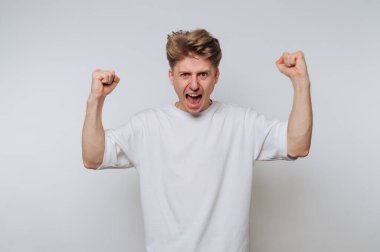 Beyaz tişörtlü genç adam heyecanını yumruklarıyla dile getiriyor..