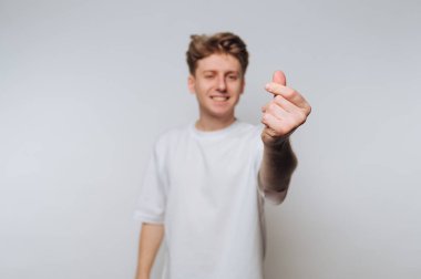 Beyaz gömlekli genç adam kalp hareketi yapıyor..