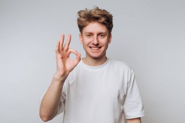 Beyaz tişörtlü genç adam iyi bir jest yapıyor.