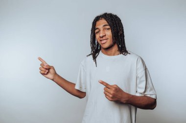 Saçları yana taranmış genç bir adam, düz bir arkaplanda beyaz bir tişört giyiyor..