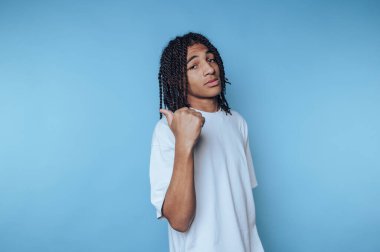 Mavi arka planda beyaz tişörtlü rastalı genç adam.