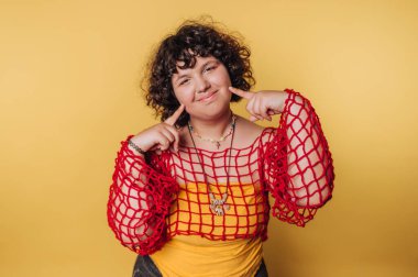 Sarı arka planda kırmızı bir ağ içinde gülümseyen kişi..