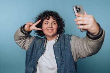Akıllı telefonuyla selfie çeken kişi barış işareti yapıyor..