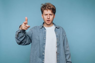 Kot gömlekli genç adam şaşırmış bir ifadeyle işaret ediyor..