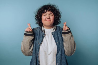 Kıvırcık saçlı, kot ceket giyen biri..