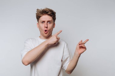 Beyaz tişörtlü genç adam şaşırmış ifadesini gösteriyor.