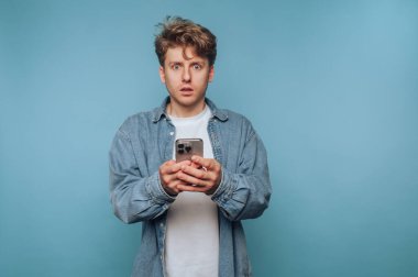 Kot gömlekli genç adam akıllı telefona şaşırmış görünüyor..