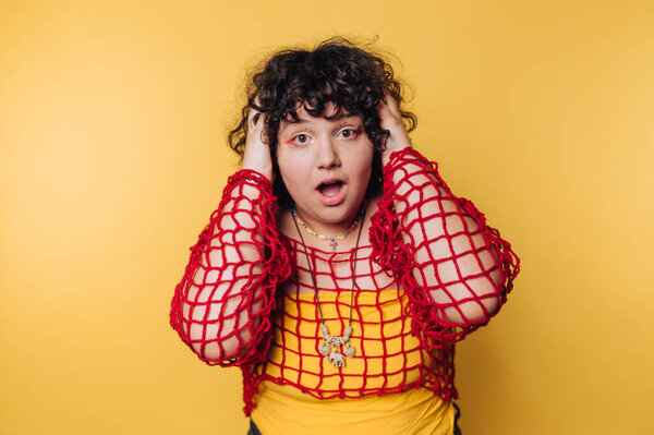 Удивлённая женщина в красной сетке на жёлтом фоне.