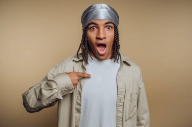 Saçları örgülü, kendini gösteren şaşırmış genç bir adam..