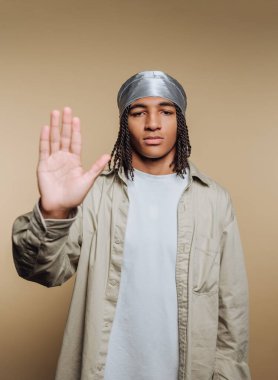 Örgülü genç adam durağan giyinmiş, el kaldırıyor..