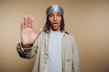 Şaşırmış yüz ifadesiyle genç adam dur işaretinde el ele tutuşuyor..