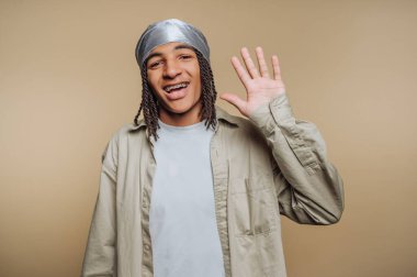 Örgülü ve kameraya el sallayan genç biri..