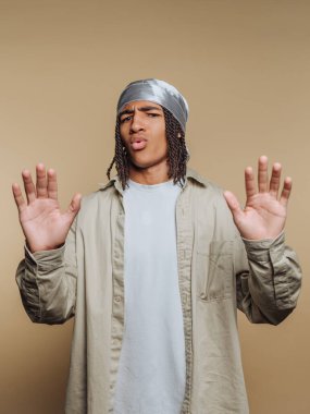 Rastalı genç adam bandana takıyor, el kaldırıyor..