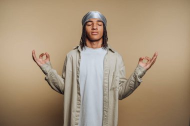 Genç adam kapalı gözlerle ve el hareketleriyle meditasyon yapıyor.