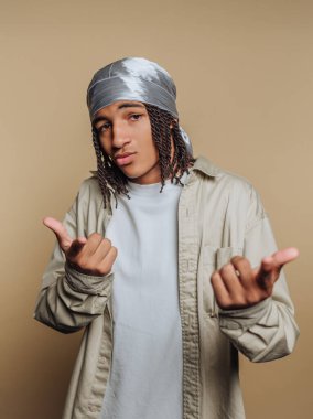 Durag ve günlük kıyafetleri olan genç bir adam kendine güvenerek poz veriyor..