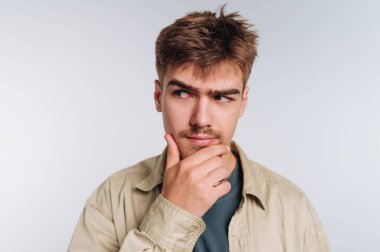 Düşünceli bir ifadesi olan genç bir adam, elleri çenesinde, tarafsız bir geçmişi var..