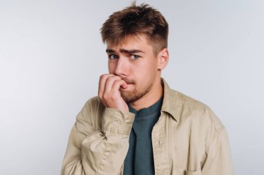 Endişeli görünen genç bir adam, tırnaklarını yiyor, üstünkörü giyiniyor, tarafsız bir geçmişi var.