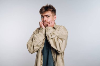 Genç adam endişeli görünüyor, tırnaklarını yiyor, günlük kıyafetler giyiyor..