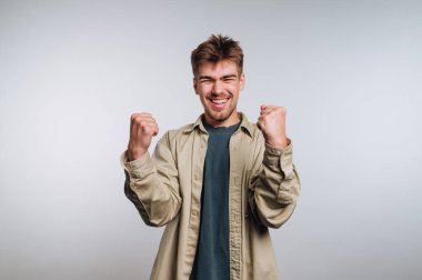 Genç adam yumruklarıyla kutluyor, gülümsüyor.