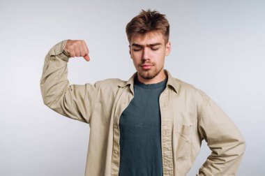 Genç adam pazılarını esnetiyor, günlük kıyafetler giyiyor, tarafsız bir altyapısı var..