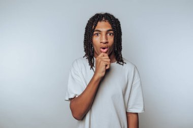 Şaşırmış ifadesi olan genç bir adam, elleri çenesinde, tarafsız bir geçmişi var..