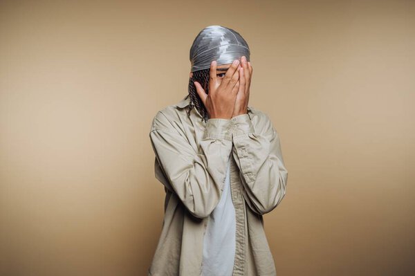 Лицо, прикрывающее лицо руками на бежевом фоне