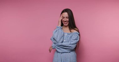 footage of young woman elegantly poses, showcasing a casual yet stylish attire on pink background