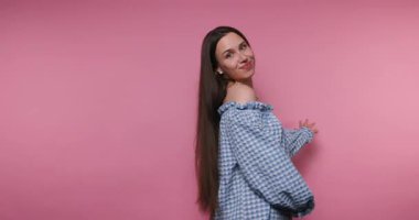 footage of young woman with long hair smiles gracefully, posing elegantly on pink background