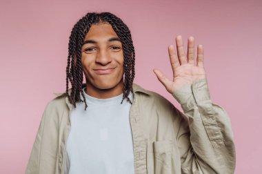 A young person with braided hair smiles and raises a hand in a friendly wave. The background is a soft pink, creating a warm and inviting atmosphere.