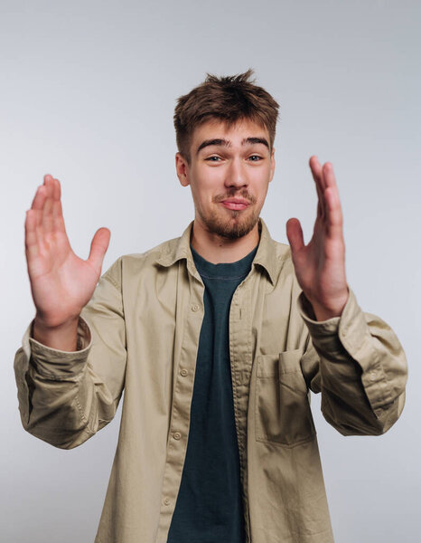 A young man stands against a plain background, expressing himself with animated hand gestures while sharing his thoughts. His facial expression shows enthusiasm and engagement.