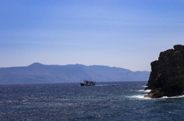 Dik kıyıları ve manzarası olan bir gemi denizde yelken açar.