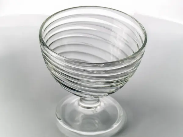 One empty glass bowl on a high stem on a white background