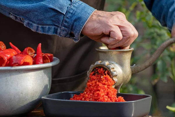 用甜椒制作自制酱汁 用磨碎机制作辣椒辣椒 人在户外的旧肉磨机上磨碎红辣椒 蔬菜沙司健康有机食品概念 — 图库照片