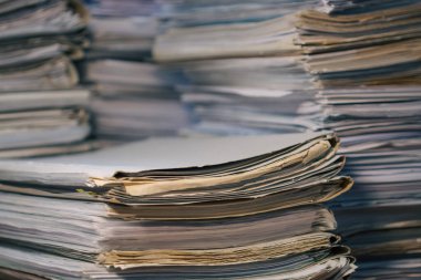 İçerideki ahşap masada şarjörlü boş kağıtlar yığını. İş yeri. Bir sürü belge, kontrat, yasal anlaşmalar, çalışma masasındaki kağıtlar. İş kavramı, çalışma, Jo