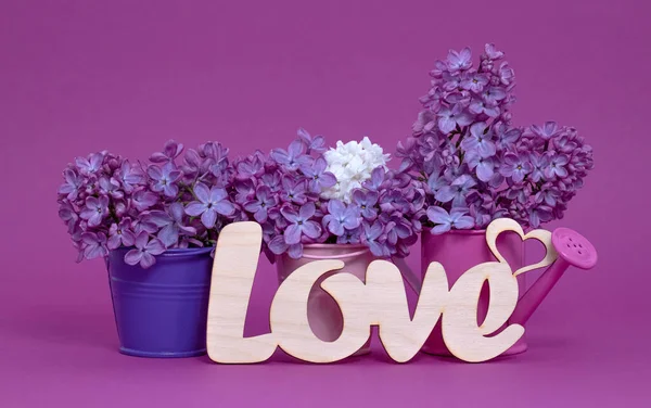 Word Love and lilac flowers on pink background. St. Valentine Day, love or wedding day concept. Romantic pink background with word Love and  flowers, copy space