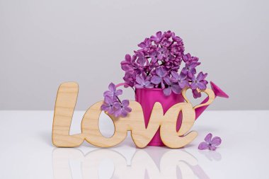 Word Love and lilac flowers on white background. St. Valentine Day, love or wedding day concept. Romantic white background with word Love and  flowers, copy space